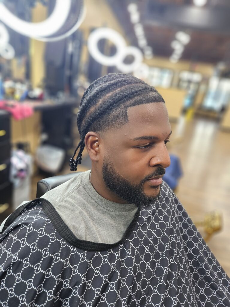 black man with braids sitting in barber chair in Boudreau's Barbershop